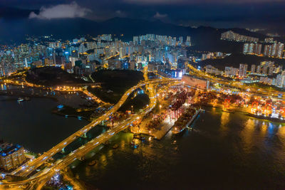 High angle view of illuminated city by sea against sky