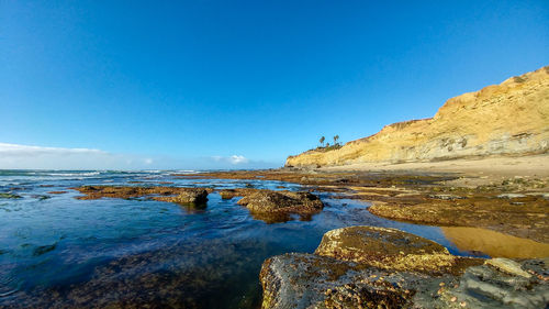 Rocks on beach against blue sky