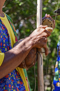 Midsection of man playing berimbau in city