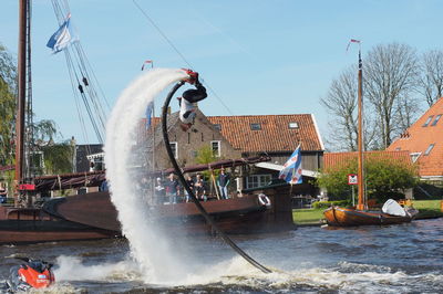 Man flyboarding over lake against sky