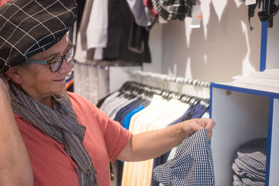 Senior woman wearing cap buying clothes at store