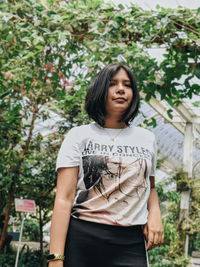 Low angle portrait of young woman standing against plants