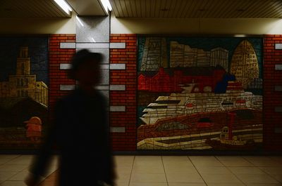 Blurred man walking in subway along graffiti wall