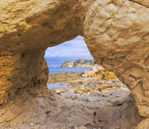 Natural arch in the cliff's surrounding cala blanca beach, javea, alicante, spain.