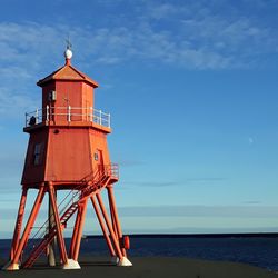Lifeguard tower on beach against blue sky