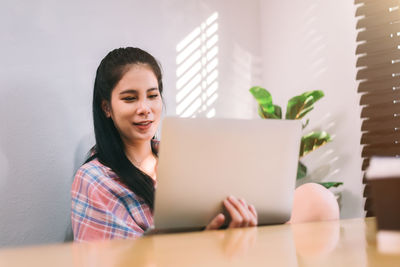 Portrait of young woman using laptop at home