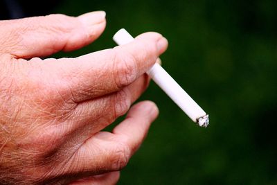 Close-up of hand holding cigarette