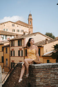 Full length of young woman standing against building