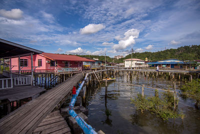 Bridge over canal by buildings against sky