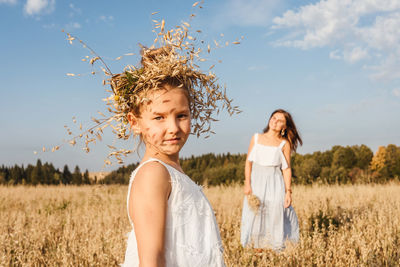 Portrait of girl wearing plants on head with mother in background