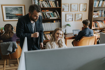 Smiling young female student with professor in library