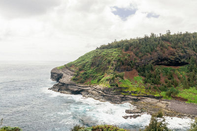 Scenic view of cliff by sea against sky