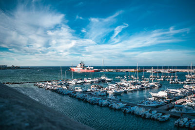 Sailboats moored at harbor against sky