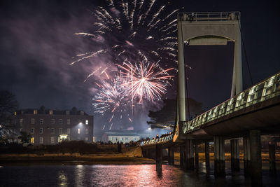 Firework display over river against sky at night