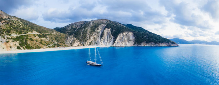 Sailboat in sea against mountains