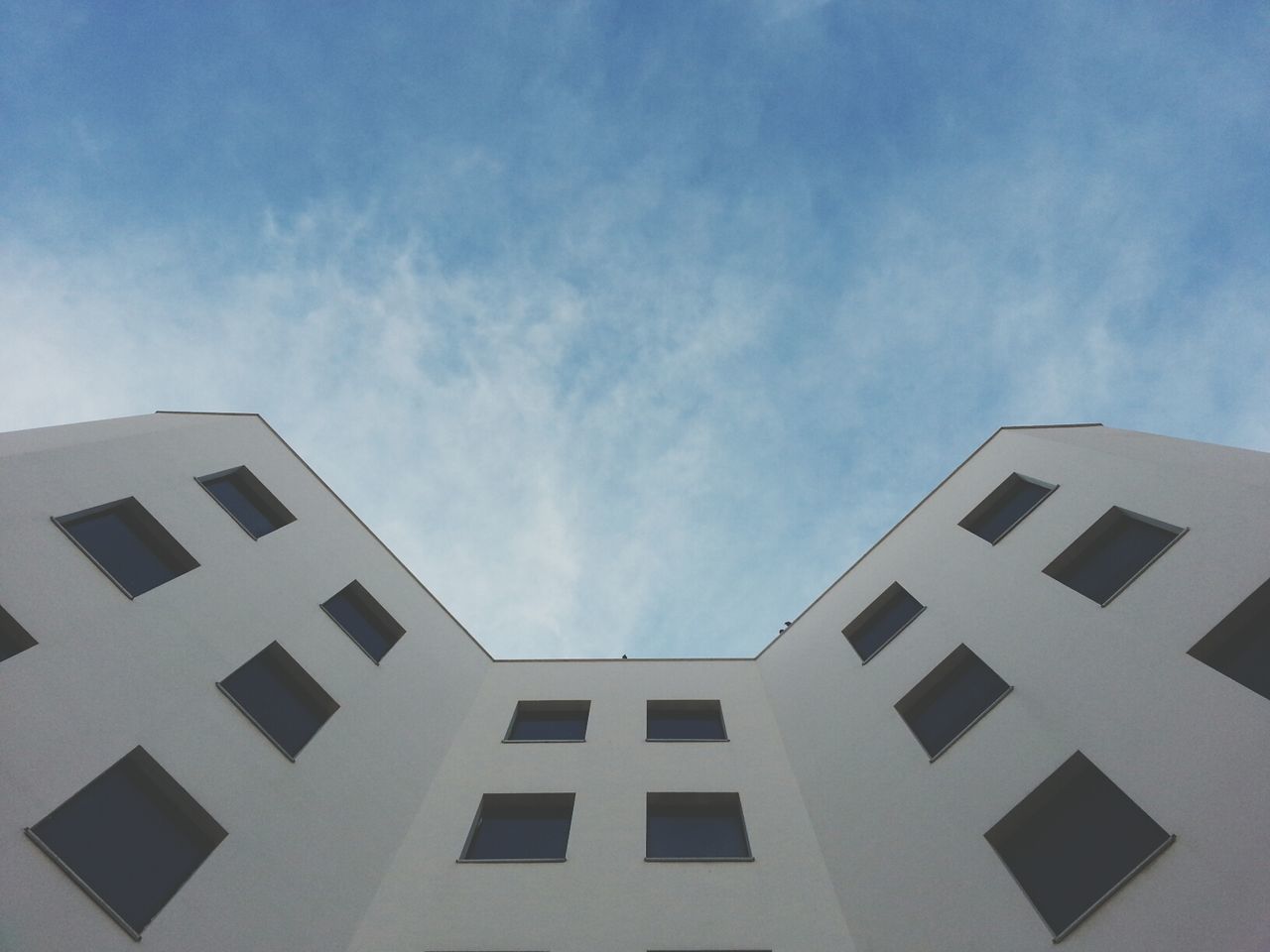 architecture, building exterior, built structure, low angle view, sky, window, building, cloud - sky, cloud, day, outdoors, city, no people, blue, residential building, cloudy, residential structure, glass - material, sunlight, in a row