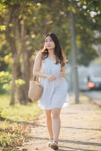 Full length of young woman standing against trees