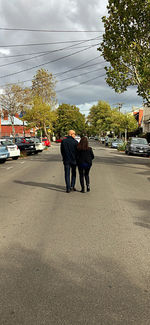 Rear view of men walking on road in city