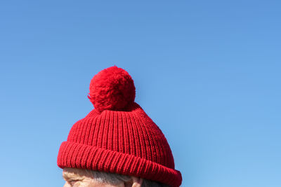 Cropped image of man wearing red knit hat against clear blue sky