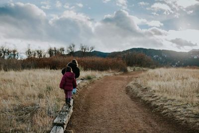 Rear view of girl walking on road against sky