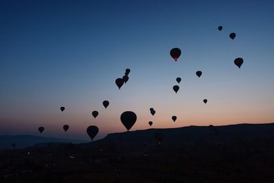 Silhouette of hot air balloons against sky during sunset