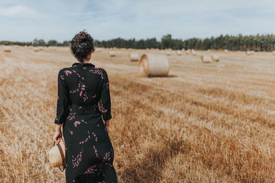 Rear view of woman standing in farm against sky