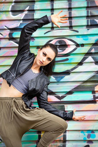 Portrait of young woman posing against graffiti wall