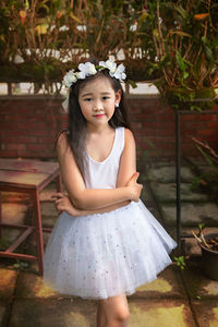 Portrait of cute girl standing against brick wall