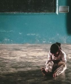 Rear view of boy sitting in swimming pool