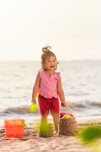 Girl with toys standing at beach