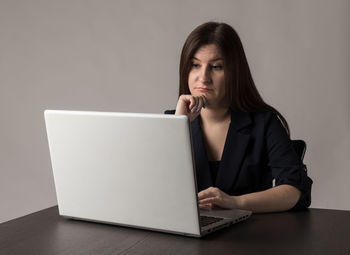 Portrait of woman using phone while sitting on table