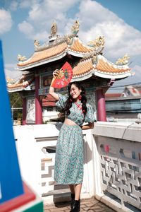 Portrait of woman in blue modern cheongsam holding a red fan at chinese temple 