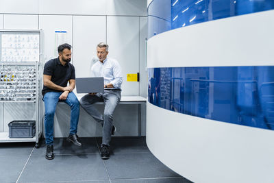 Businessman discussing with colleague over laptop at modern factory