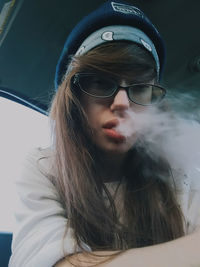 Portrait of young woman smoking in car