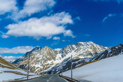 Road by snowcapped mountains against sky