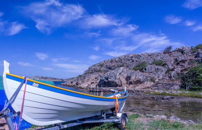 Boats moored on shore against blue sky