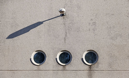 Concrete wall with three round windows and with a lamp above