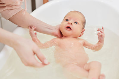Cropped hands of mother bathing baby