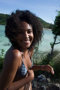 Portrait of happy young woman with curly hair against lake