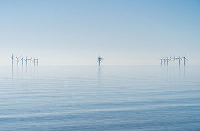 Offshore wind turbines generating renewable electricity and energy  atmospheric background image