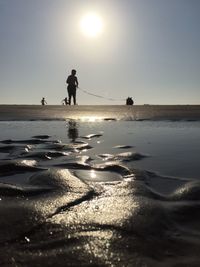 Silhouette man standing with dog at beach