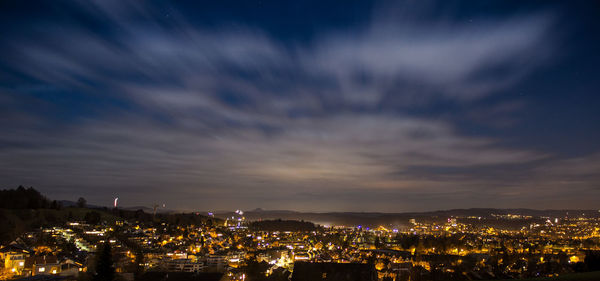 Illuminated cityscape against sky at night