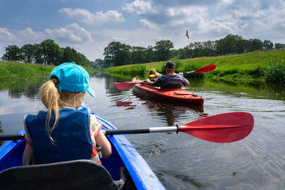 Rear view of men sitting on boat in river