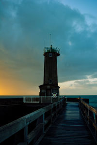 Pier on sea against cloudy sky