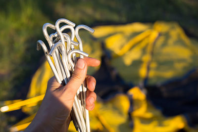 Aluminum stakes for the installation of a tourist yellow tent in the hand close-up. lightweight