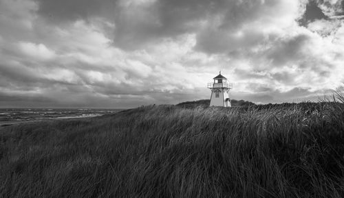 Lighthouse by sea against sky