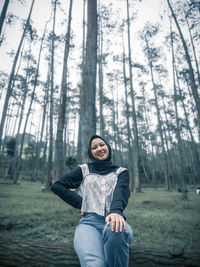 Portrait of young woman sitting on land in forest