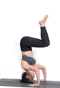 Full length of woman doing yoga on white background