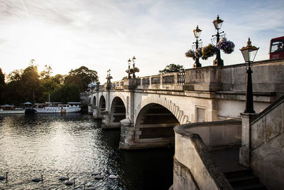 Bridge over river in city against sky