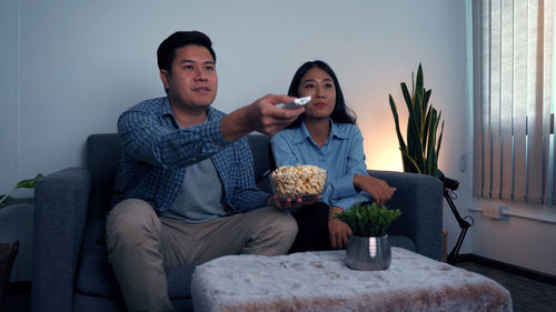 Young couple looking away while sitting at home